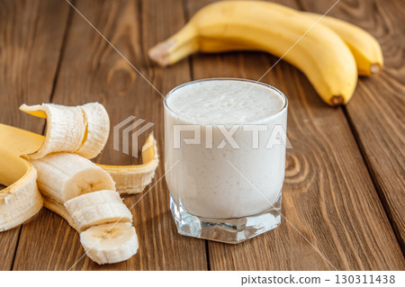 smooth banana smoothie fresh bananas on wooden table in cozy kitchen during daylight. closeup. smooth banana smoothie fresh bananas on wooden table in cozy kitchen during daylight. closeup. 130311438