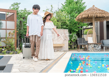 Young Asian couple walking by the poolside of a resort hotel (travel, honeymoon, vacation) 130311510