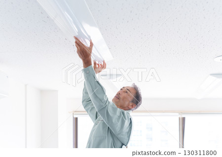 Senior male worker installing lights 130311800
