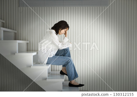 中年婦女坐在樓梯上,向下看,消極 中年婦女坐在樓梯上,向下看,消極 130312155
