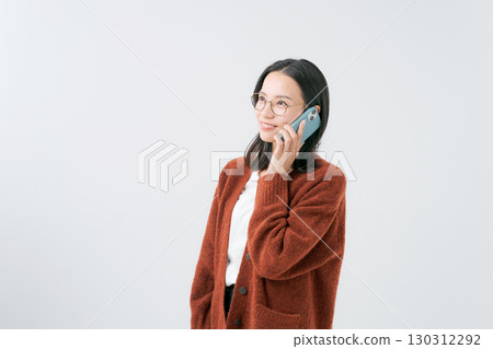 A woman in a sweater talking on a smartphone 130312292
