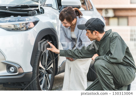 一名男性汽車修理工向一名女性司機解釋汽車輪胎 130313004