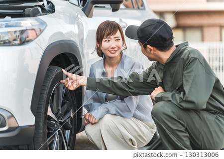 一名男性汽車修理工向一名女性司機解釋汽車輪胎 130313006