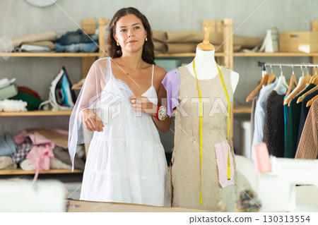 Fashion designer fitting dress on mannequin in dressmaker studio 130313554