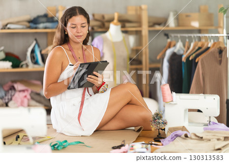 dressmaker draws a sketch on a tablet in the workshop dressmaker draws a sketch on a tablet in the workshop 130313583