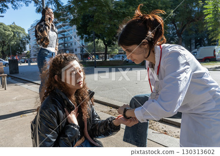 Doctor checking pulse of sick woman on street 130313602