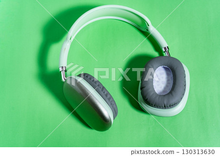 Wireless headphones lying on vibrant green background Wireless headphones lying on vibrant green background 130313630