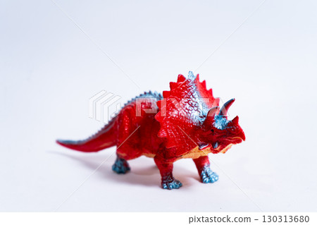 Red triceratops dinosaur toy standing on white background 130313680