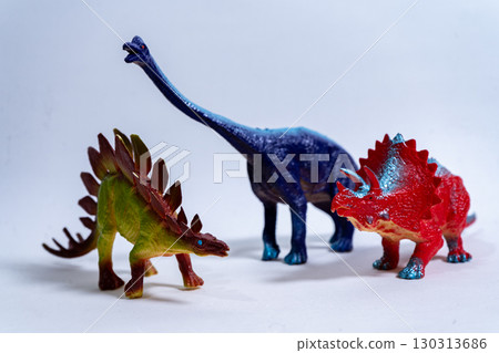 Colorful plastic dinosaurs standing on white background Colorful plastic dinosaurs standing on white background 130313686