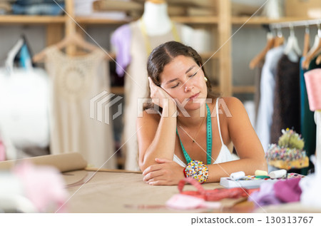 Tired female fashion designer sleeping at worktable in sewing studio 130313767