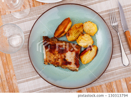 Grilled pork ribs with vegetable garnish of baked potatoes 130313794