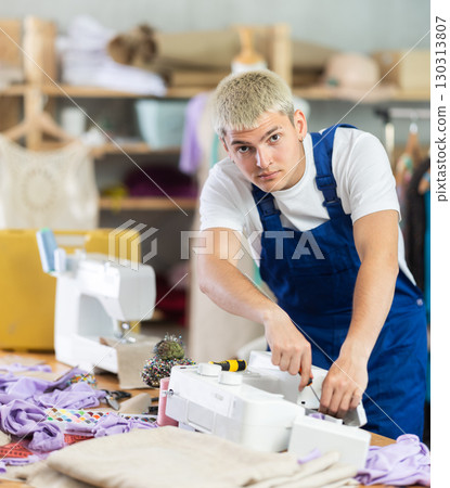 Repairman repairing sewing machine in workshop 130313807