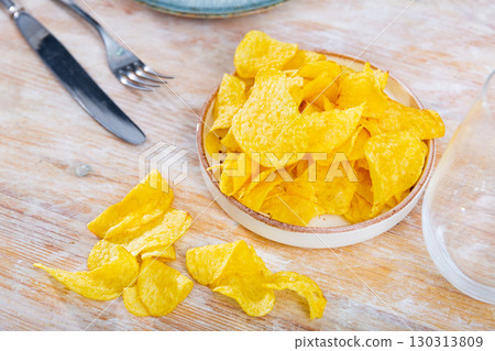 Crispy salty potato chips with natural taste on plate 130313809