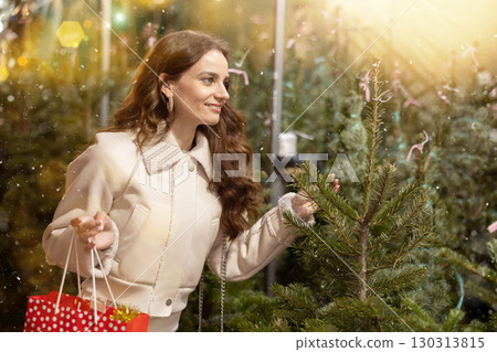 Smiling woman choosing fir tree for New Year celebration at street fair 130313815