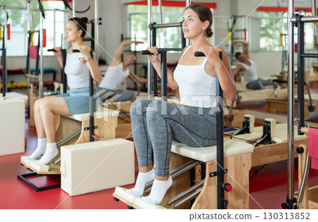 Young girl training her legs in seated position on combo chair 130313852