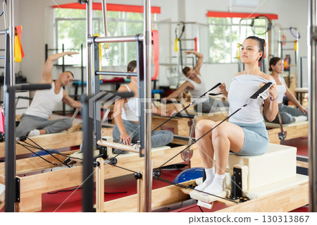 Young girl doing arm exercises on cable reformer device 130313867