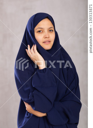 Portrait of young positive woman in khimara posing in studio 130313871