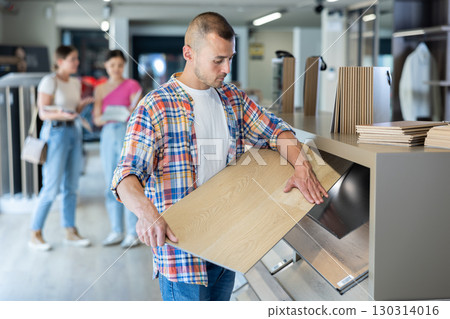 Male buyer carefully selects laminate flooring in hardware store Male buyer carefully selects laminate flooring in hardware store 130314016