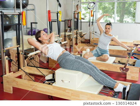 Young woman training her abs on pilates machine 130314024