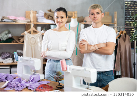 Young male and female dressmakers posing in sewing workshop 130314030