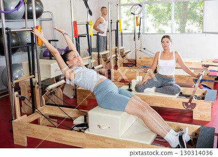 Young girl doing press exercises on reformer device Young girl doing press exercises on reformer device 130314036