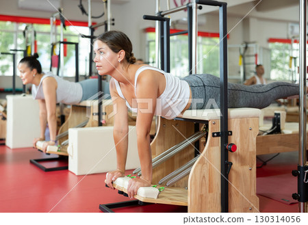 Active young girl doing press exercises on combo chair Active young girl doing press exercises on combo chair 130314056