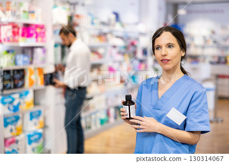 Female pharmacist offering product, working in drugstore 130314067