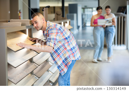 Young man choosing laminate flooring in store 130314149