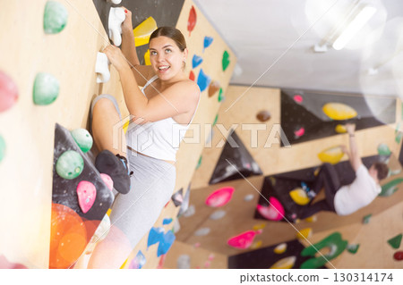 Young Europian woman climbs steep artificial wall in sports complex and trains endurance Young Europian woman climbs steep artificial wall in sports complex and trains endurance 130314174