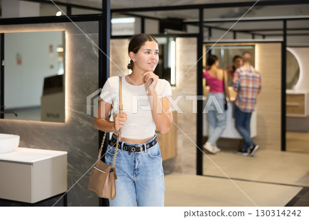 Interested young girl choosing bathroom fixtures in specialized showroom 130314242