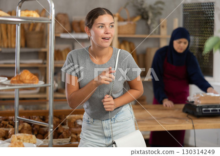 Girl choosing fresh pastries from display at Muslim bakery 130314249