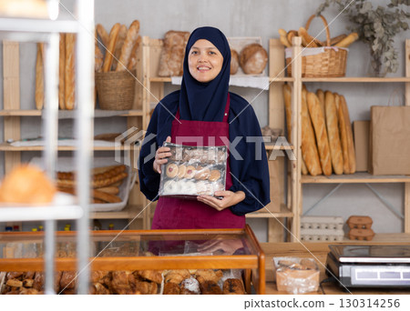 Middle-aged Muslim saleswoman holds cookie box in bakery 130314256