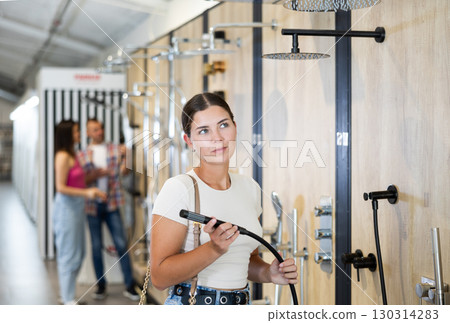 Young woman choosing shower head in store Young woman choosing shower head in store 130314283