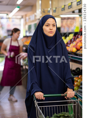 Portrait of young woman shopper in hijab in supermarket 130314330