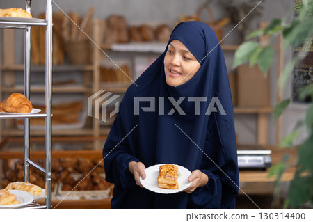 Asian Muslim girl in hijab customer holding disposable plate with burger snack in bakery Asian Muslim girl in hijab customer holding disposable plate with burger snack in bakery 130314400