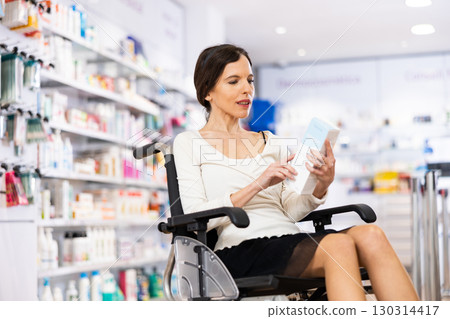 Disabled woman choosing medicine in pharmacy Disabled woman choosing medicine in pharmacy 130314417
