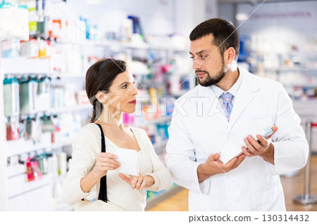 Male pharmacist advising woman customer in drugstore Male pharmacist advising woman customer in drugstore 130314432