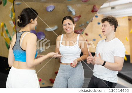 Asian girl, European woman and teenage guy - group of friends stand actively relaxing in climb hall Asian girl, European woman and teenage guy - group of friends stand actively relaxing in climb hall 130314493