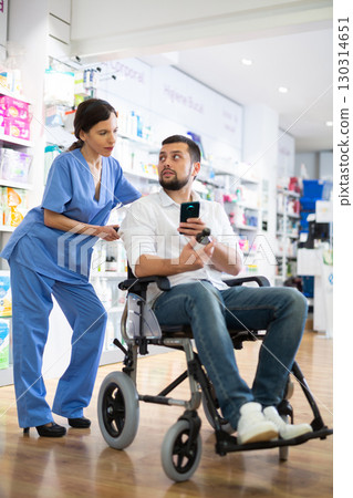 Female pharmacist advising disabled man in drugstore Female pharmacist advising disabled man in drugstore 130314651