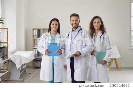 Portrait of happy team of young medical doctors looking at camera and smiling in clinic Portrait of happy team of young medical doctors looking at camera and smiling in clinic 130314921