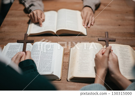 Group of Christians sit together and pray around a wooden table with blurred open Bible pages in their homeroom. Group of Christians sit together and pray around a wooden table with blurred open Bible pages in their homeroom. 130315000