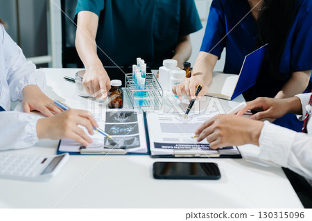 Medical team having a meeting with doctors in white lab coats and surgical scrubs seated at a table discussing a patients working online using computers Medical team having a meeting with doctors in white lab coats and surgical scrubs seated at a table discussing a patients working online using computers 130315096