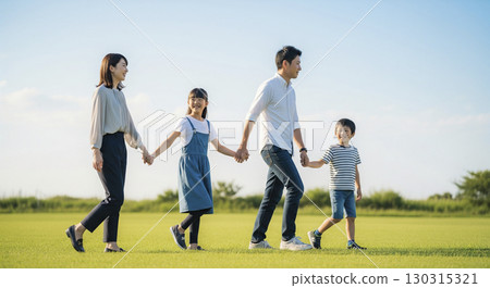 Family walking hand in hand in a field Family walking hand in hand in a field 130315321