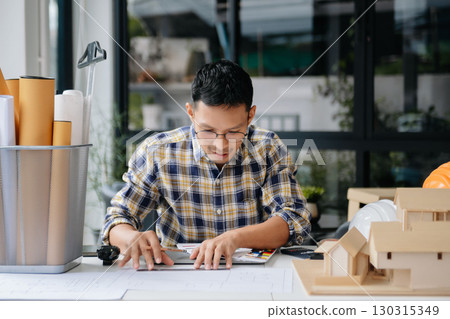 business man hand working and laptop with on on architectural project at construction site at desk 130315349