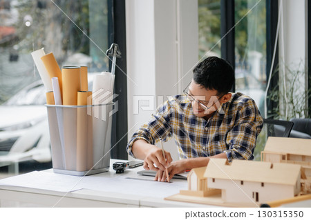 business man hand working and laptop with on on architectural project at construction site at desk business man hand working and laptop with on on architectural project at construction site at desk 130315350
