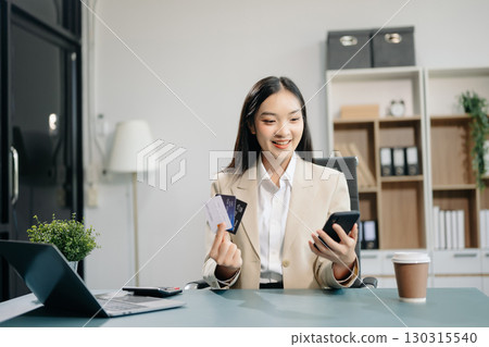 Woman using smart phone for mobile payments online shopping, omni channel, sitting on table Woman using smart phone for mobile payments online shopping, omni channel, sitting on table 130315540