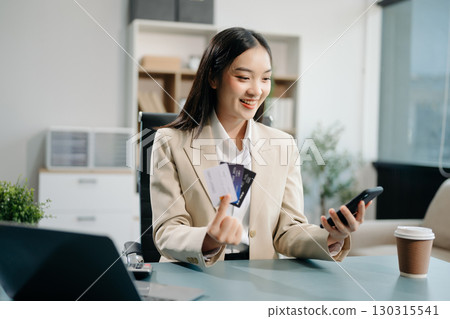 Woman using smart phone for mobile payments online shopping, omni channel, sitting on table Woman using smart phone for mobile payments online shopping, omni channel, sitting on table 130315541