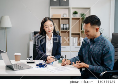 Asian people car salesman or sales manager offers to sell a car and explains of signing a car contract Asian people car salesman or sales manager offers to sell a car and explains of signing a car contract 130315585