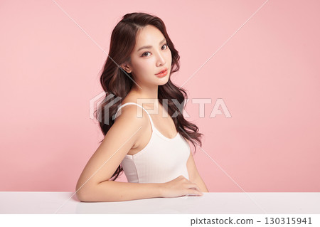 A beautiful young Asian woman with clean, fresh skin against a pink background. Skincare, facial treatment, cosmetology, beauty, and spa. An elegant portrait of an Asian woman. A beautiful young Asian woman with clean, fresh skin against a pink background. Skincare, facial treatment, cosmetology, beauty, and spa. An elegant portrait of an Asian woman. 130315941