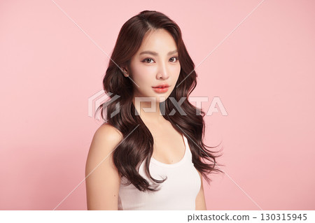 A beautiful young Asian woman with clean, fresh skin against a pink background. Skincare, facial treatment, cosmetology, beauty, and spa. An elegant portrait of an Asian woman. 130315945